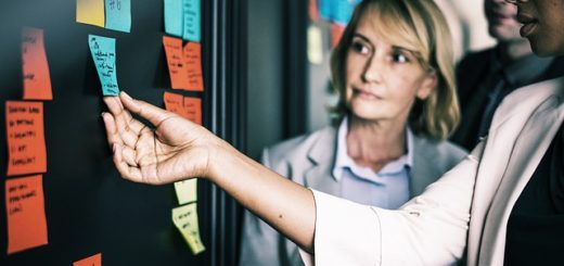 Team scrutinizing postits on glass wall